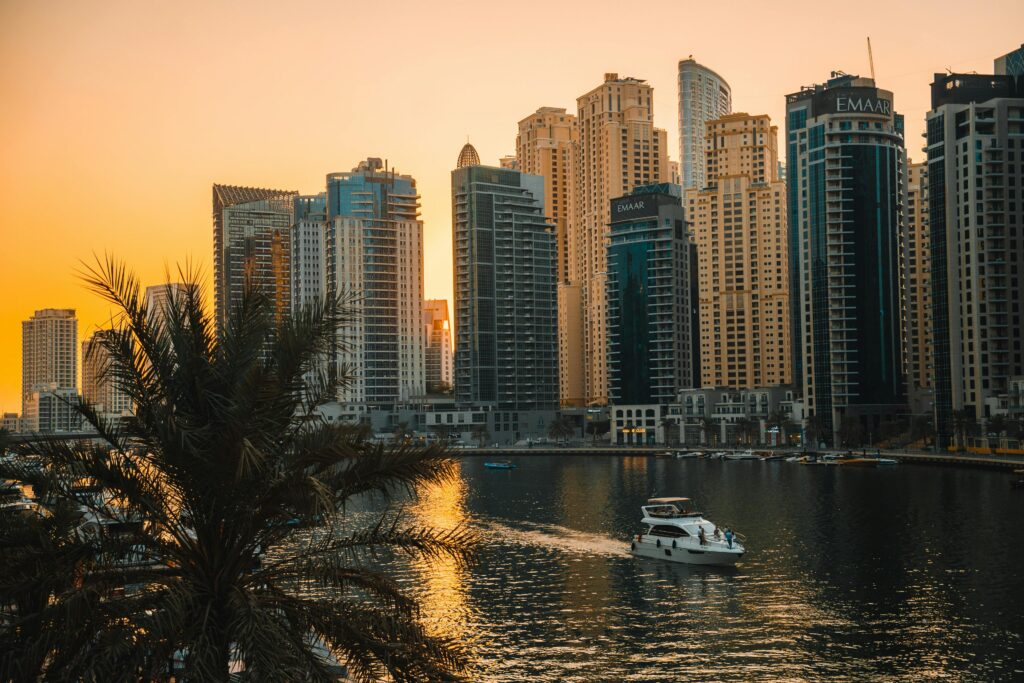 Sunset over Dubai Marina skyline with luxury yachts on the water and high-rise buildings.
